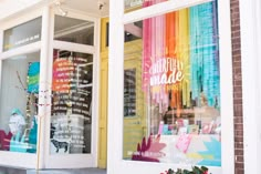 there is a store front with many different colored ribbons in the window and on the sidewalk