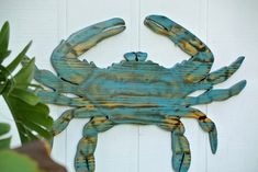 a blue metal crab hanging on the side of a white door