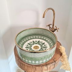 a green and white bowl sink sitting on top of a wooden stand next to a faucet