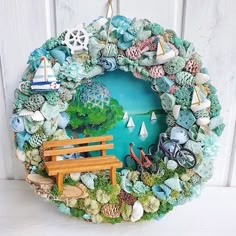 a wreath made out of rocks and seashells with a bench in the middle