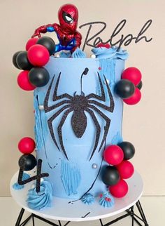 a spiderman birthday cake is decorated with balloons