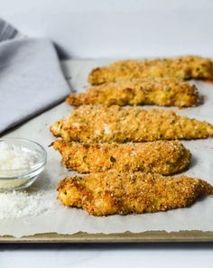 some fried food on a tray next to a small bowl and spoon with white rice