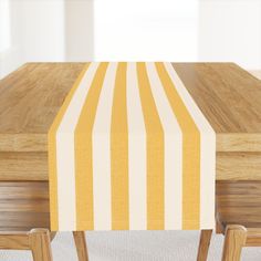 a wooden table topped with a yellow and white striped table cloth on top of it