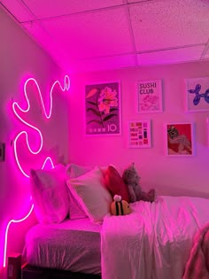 a bedroom with pink lighting and pictures on the wall above the bed, along with a teddy bear