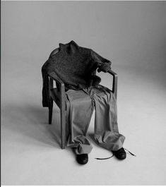 a black and white photo of a person sitting in a chair with an umbrella over their head