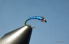 a blue and black fish hook on top of a metal pole with sky in the background