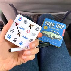 a person holding a game in their hand while sitting on the back seat of a car