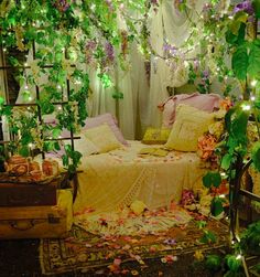 a bed covered in lots of flowers and greenery next to a window with curtains