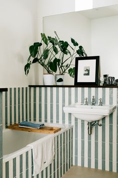 a bathroom with green and white striped tiles on the walls, a sink and mirror