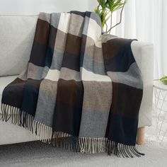 a plaid blanket draped over a couch in front of a potted plant on top of a table