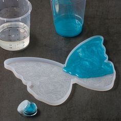 plastic cups and spoons are sitting on the table next to each other, including one with a blue butterfly