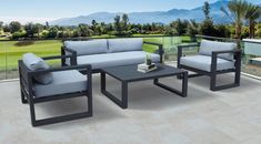 an outdoor patio furniture set with grey cushions and white pillows on a balcony overlooking a golf course