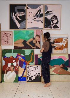 a woman is standing in front of many paintings