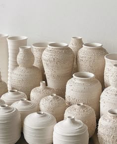 many white vases are lined up against the wall