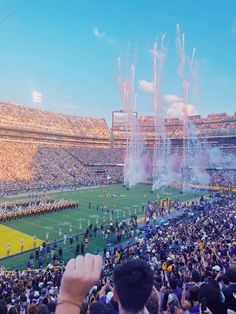 a stadium filled with lots of people watching fireworks go off in the sky over a football field