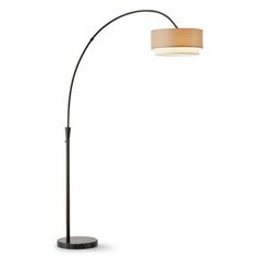 a floor lamp with a white shade on top and a black base, in front of a