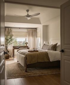 a bedroom with a bed, desk and ceiling fan in the middle of the room