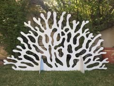 a large white sculpture sitting on top of a lush green field next to a tree