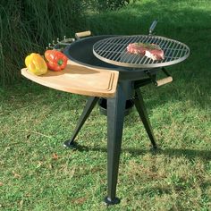 an outdoor bbq grill with vegetables and meat cooking on the top, sitting in grass