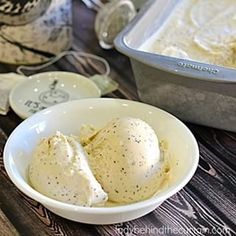 two scoops of ice cream in a bowl on a wooden table next to an oven