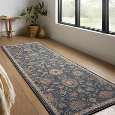 a large blue rug is on the floor in front of a window with a potted plant next to it