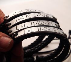 a person holding three bracelets with names engraved on the sides and numbers attached to them