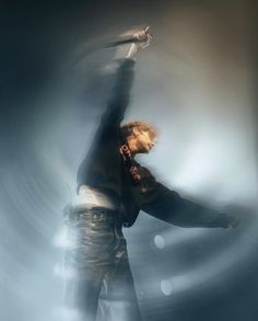 a man in black shirt and jeans standing on stage with his arms out to the side