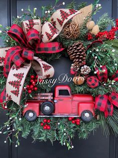 a christmas wreath with a red truck and pine cones