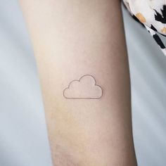 a small cloud tattoo on the left inner arm, with a black outline above it