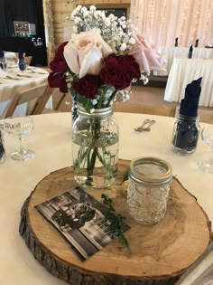 a vase filled with roses sitting on top of a wooden slice at a wedding reception