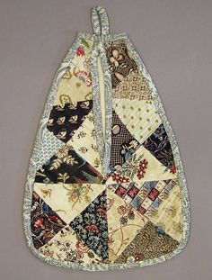 an oven mitt made out of old quilts on a gray background with white trim