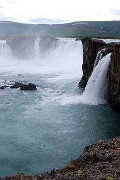 the water is blue and green as it pours into the river from the rocks