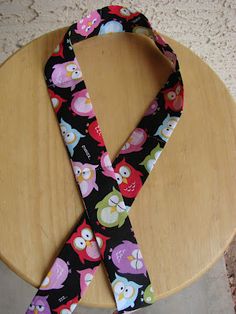 a black and pink neck tie with owls on it sitting on a wooden table next to a wall