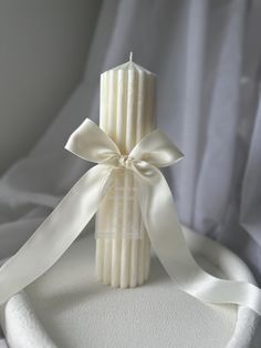 a white candle with a ribbon around it