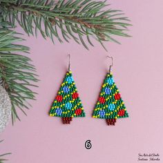 the beaded christmas tree earrings are on display next to a pine cone ornament