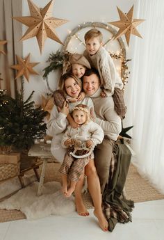 a family posing for a christmas photo in front of a star - shaped wall with lights