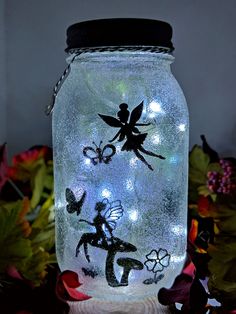 a glass jar with tinkerbells and fairy lights in it