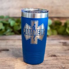 a blue travel mug with the words paramedic on it sitting on a wooden table