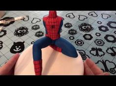 a spiderman cake sitting on top of a white frosted cake covered in fondant