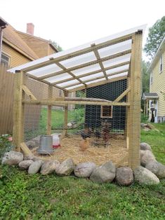 a chicken coop in the yard with rocks and grass on the ground next to it