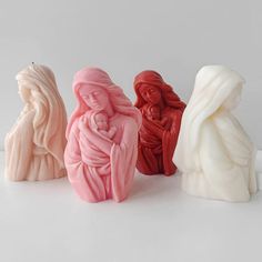 three ceramic figurines of the virgin mary and jesus holding a baby in their arms