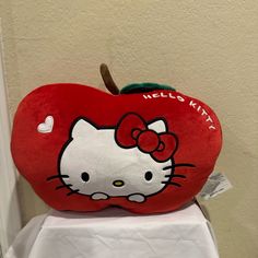 a hello kitty apple pillow sitting on top of a white tablecloth covered table cloth