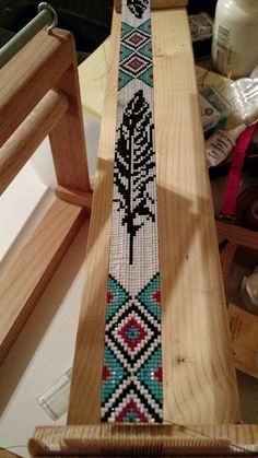 a cross stitch bracelet sitting on top of a wooden stand