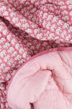 an unmade bed with pink and white sheets