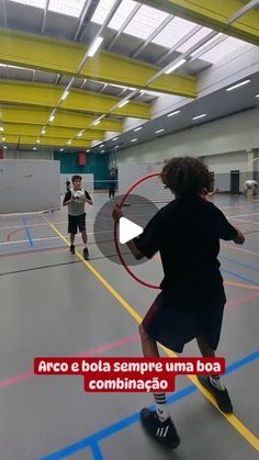 two people are playing frisbee in an indoor gym with yellow and blue lines on the floor