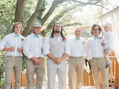 a group of men standing next to each other wearing white shirts and tan pants with green bow ties