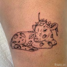 a black and white tattoo of a cow laying down