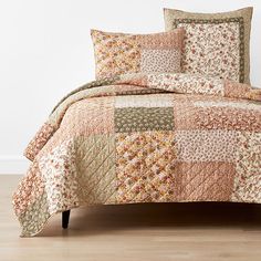 a bed covered in a multi colored patchwork comforter set with matching pillow cases