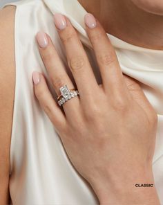 a woman's hand with a diamond ring on her left wrist, wearing a white dress