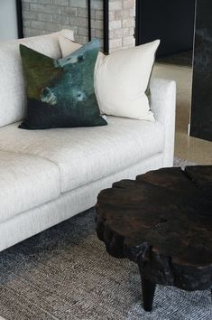 a living room with white couches and pillows on top of each other, in front of a fireplace